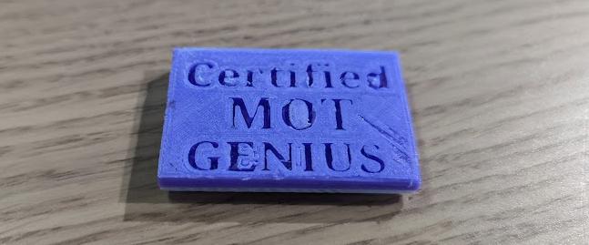 A 3D printed award that says MoT Genius